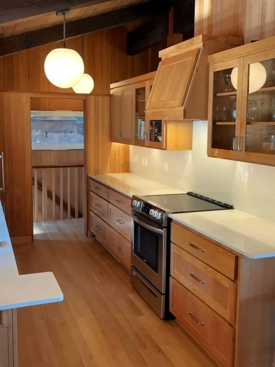 Completed Southwest Hills kitchen remodel with custom wood cabinetry, quartz countertops, updated appliances, and warm natural finishes.