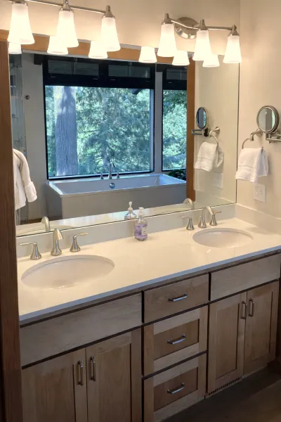 Bathroom remodel with double vanity and large window above soaking tub in a southwest hills Portland home.