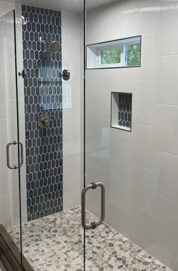 Bathroom remodel with two-person walk-in shower, glass enclosure, and navy tile accent in southeast Portland home