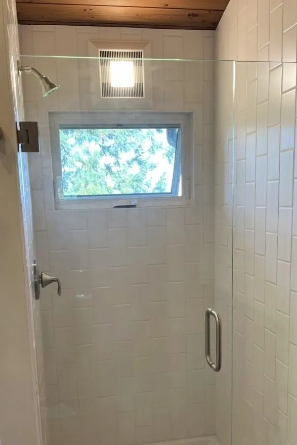 Bathroom remodel featuring walk-in shower with glass enclosure and white tile surround in southwest Portland home