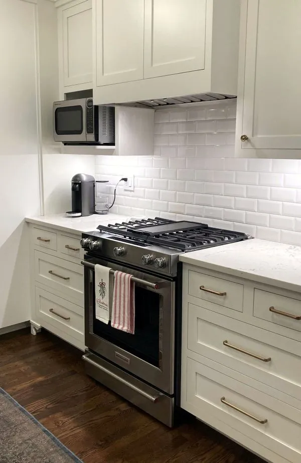 White shaker cabinets, quartz countertops, subway tile backsplash, and gas range in a remodeled Brooklyn kitchen in Southeast Portland.